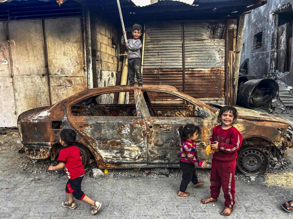 Palestinian children play with a damaged vehicle damaged during attacks in Jabalia refugee camp, April 20