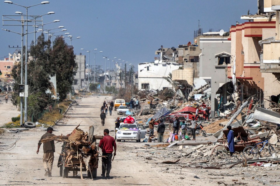 Men walk with an animal-drawn cart carrying salvaged wood from debris and trees