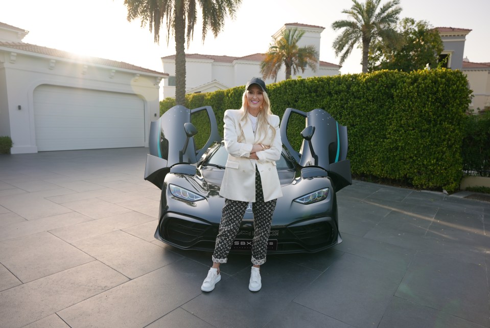 a woman stands in front of a mercedes car