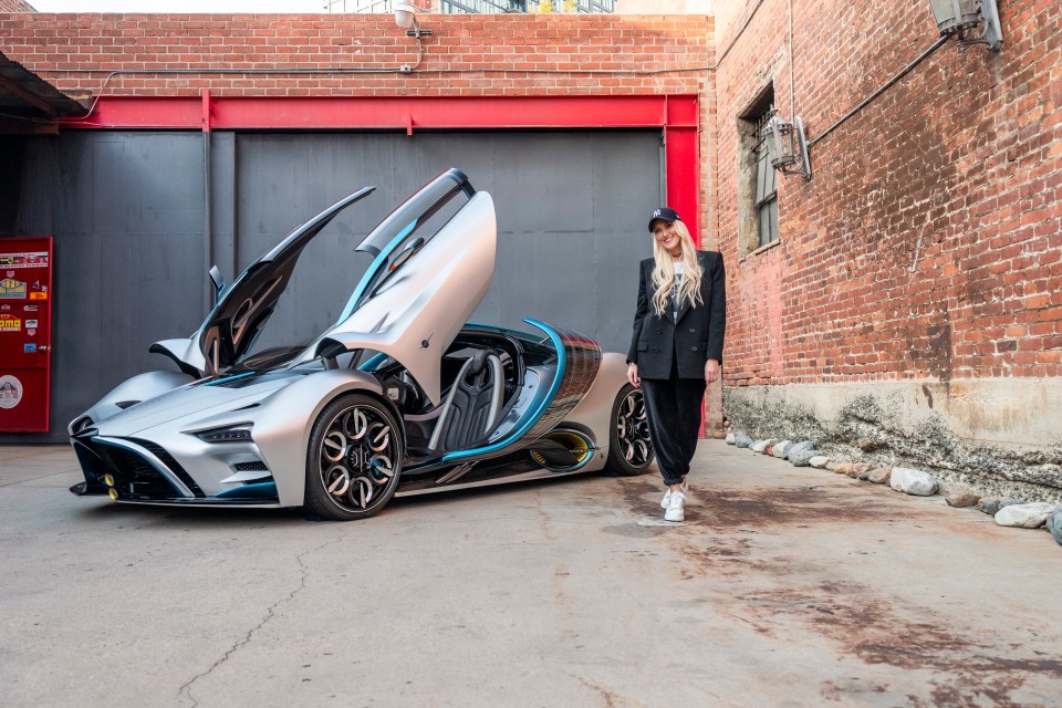 a woman stands in front of a car with the door open