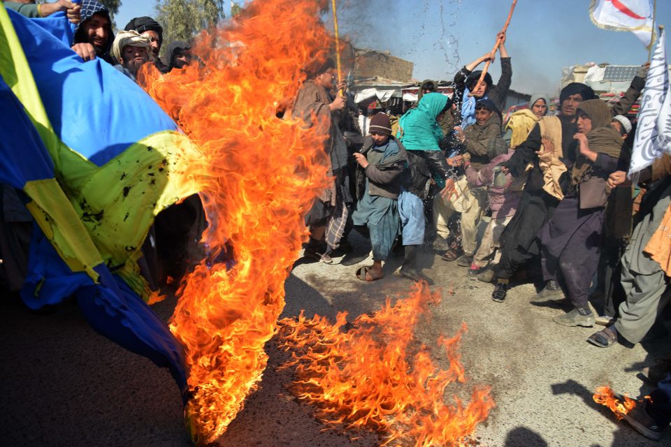 Protesters burn a flag of Sweden after reports of people burning the Muslim holy book   caused major terror risks