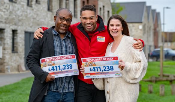 Henry (L) and his neighbour Leyla (R) with their cheques for £411,000