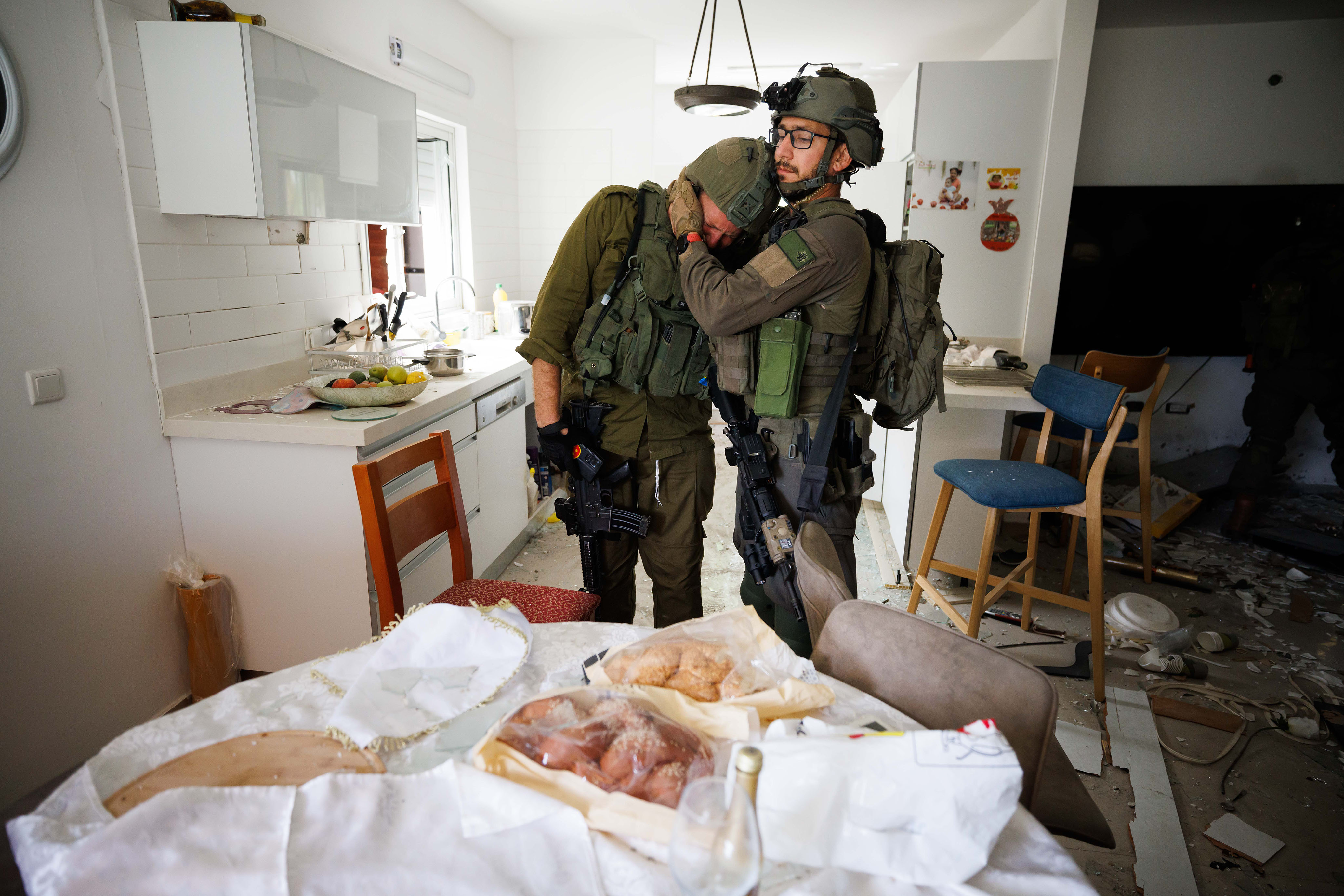 A soldier comforts his friend next to a table still holding Challah bread from Friday's Kiddush - the night before the attack