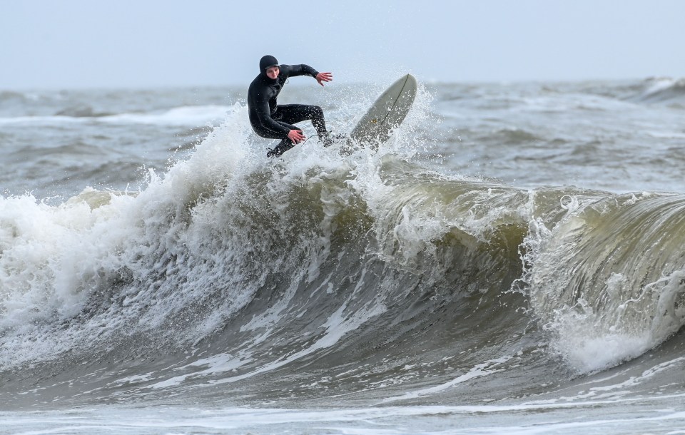 A surfer takes advantage of the huge waves whipped up by the gales