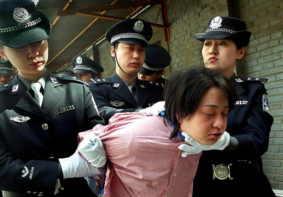 A woman prisoner escorted by police officers in China.