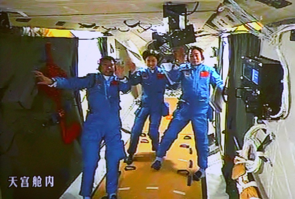 Chinese astronauts Liu Wang, Liu Yang and Jing Haipeng wave while aboard the orbiting Tiangong-1 space station