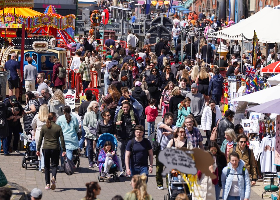 People stroll beside stalls as they enjoy the weather this bank holiday weekend