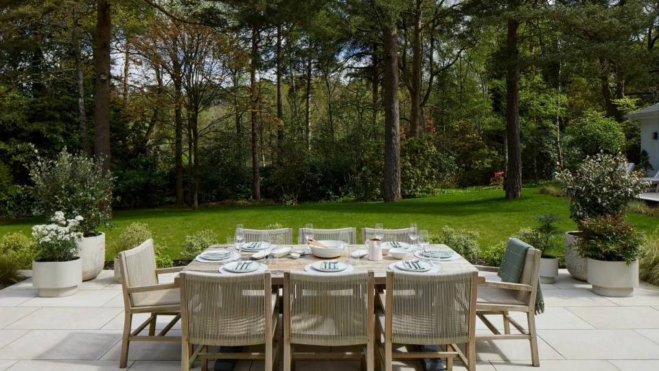 a patio with a table and chairs set for dinner