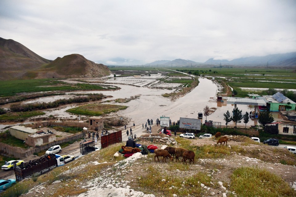 People gather by a flooded road in the Feroz Nakhchir district of Samangan on Saturday