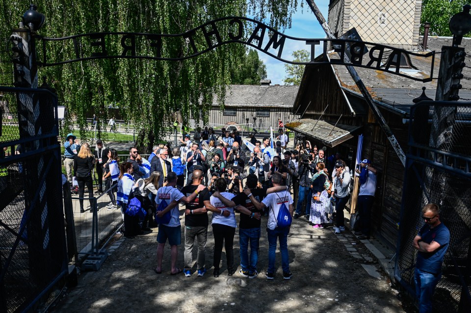 Participants carry Israel's flag and hold banners asking for Israeli hostages release under Auschwitz's entrance gate bearing the motto Arbeit Macht Frei - work brings freedom