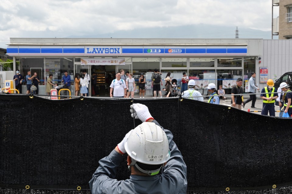 A worker installs a barrier to block the sight of Japan’s Mount Fuji emerging from behind a convenience store