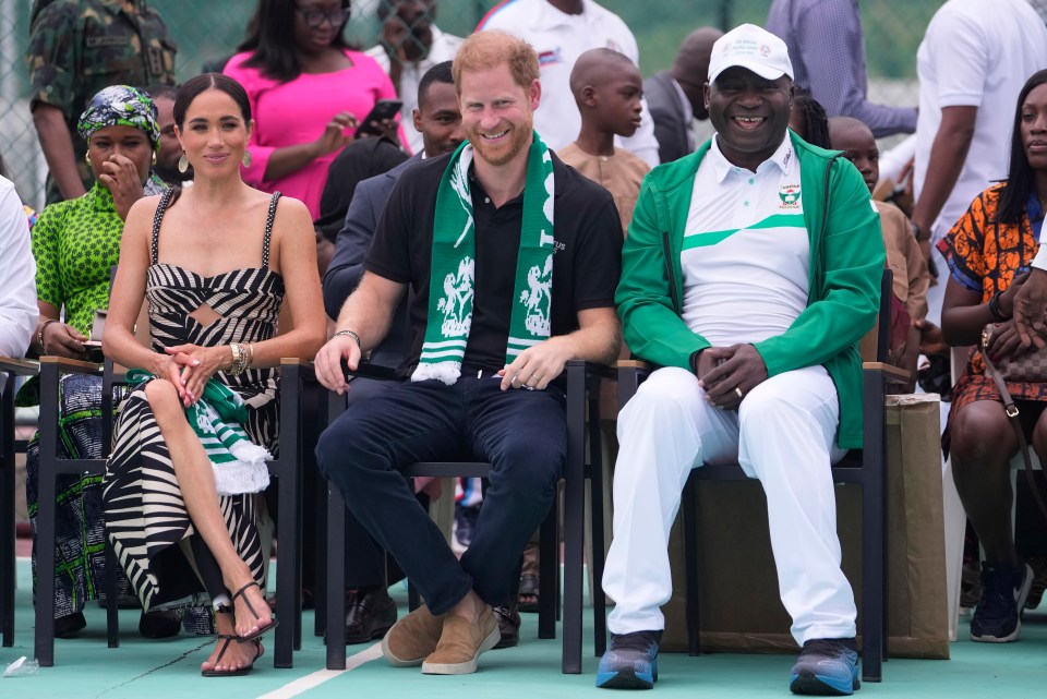 Prince Harry and Meghan, left, Nigeria chief of Defence Staff, General Christopher Gwabin Musa, right, watch an exhibition sitting volleyball match in Abuja, Nigeria, Saturday, May 11