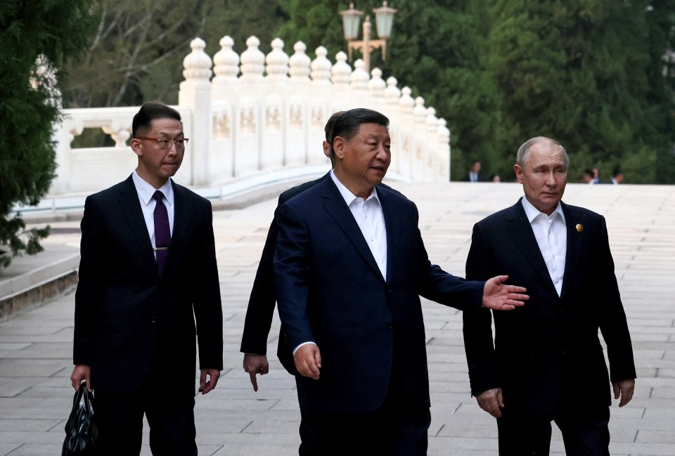 Russian President Vladimir Putin, right, and Chinese President Xi Jinping, centre, walk during an informal meeting in Beijing on Thursday