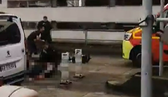 Officers attend to their colleague who lies on the ground bleeding