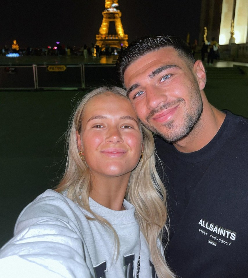 a man and a woman are posing for a picture in front of the eiffel tower