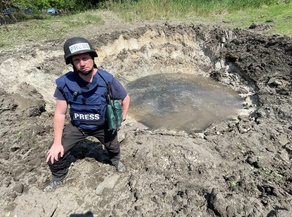 Sun man Paul Sims kneels at a crater made by a Russian S300 missile on the first strike