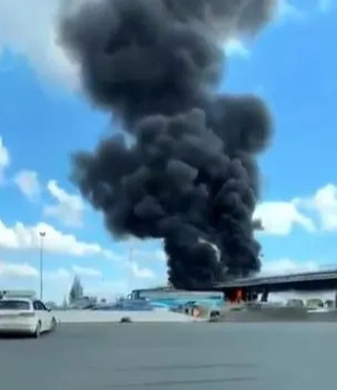 Thick plumes of black smoke can be seen billowing into the air from the coaches