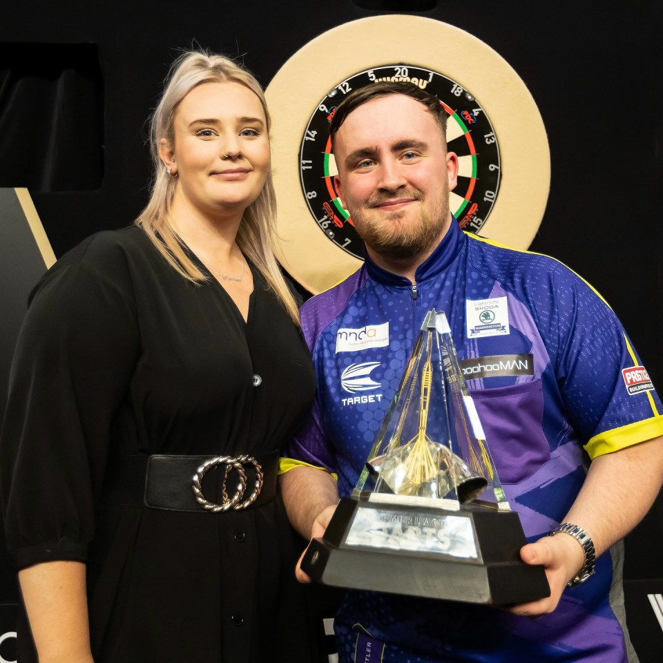 The loved-up couple posing with the trophy after he became the youngest Premier League Darts champion