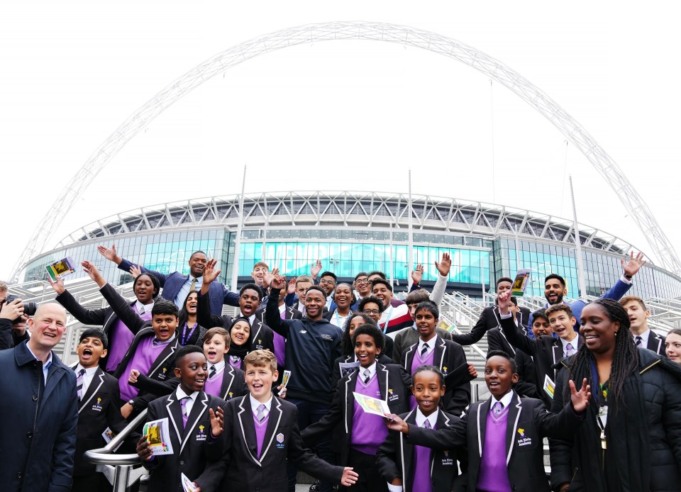 WEMBLEY, ENGLAND - NOVEMBER 16: Raheem Sterling of Manchester City poses for pictures with students outside Wembley Stadium after launching the Raheem Sterling Foundation at Ark Elvin Academy on November 16, 2021 in Wembley, England. (Photo by Matt McNulty - Manchester City/Manchester City FC via Getty Images)