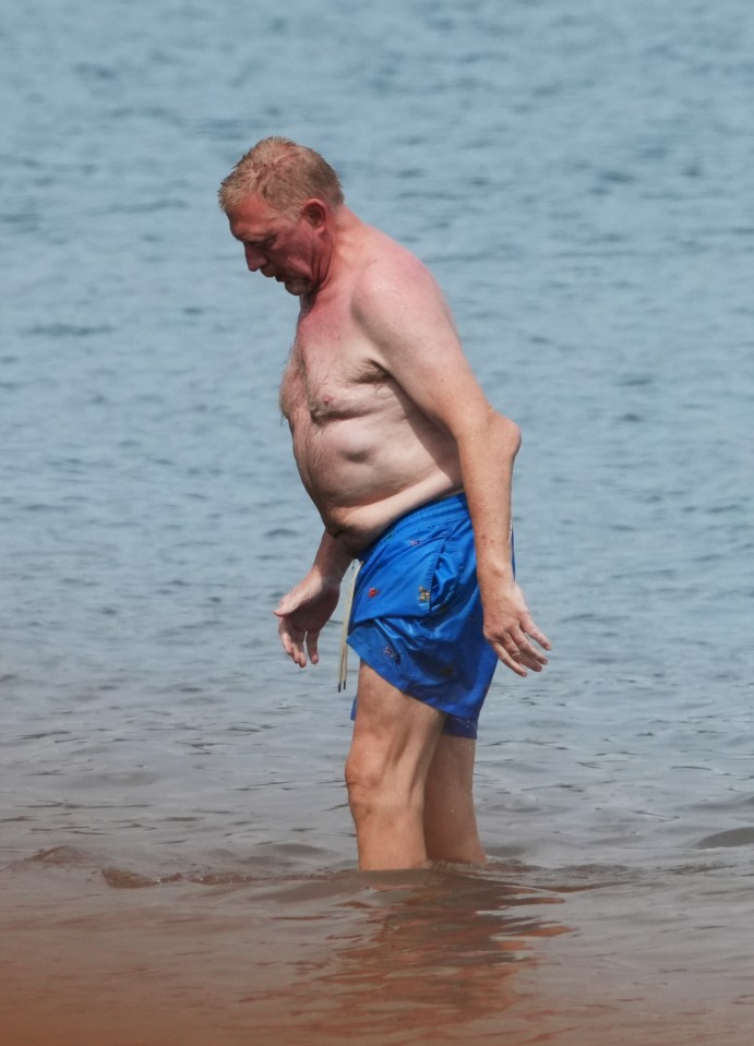 Boris Becker showed off his 'student's elbow' as he waded through the ocean