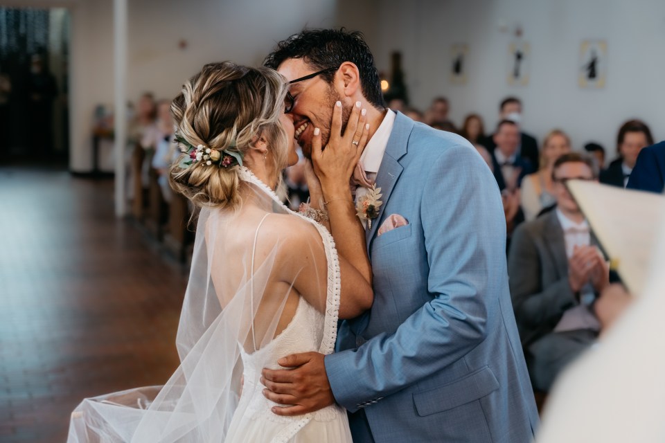 a bride and groom kiss during their wedding ceremony