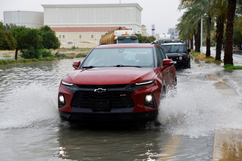 Cars drive through a flooded road following a storm in Dubai