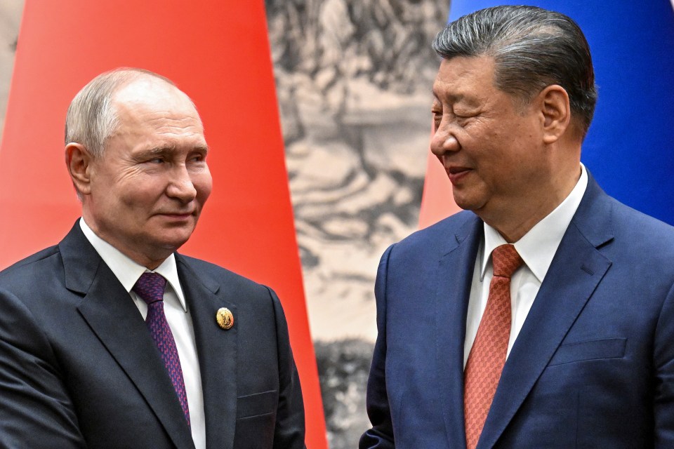 Xi and Putin look towards each other as they shake hands