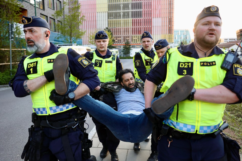 One man gets hauled away by five Swedish police officers