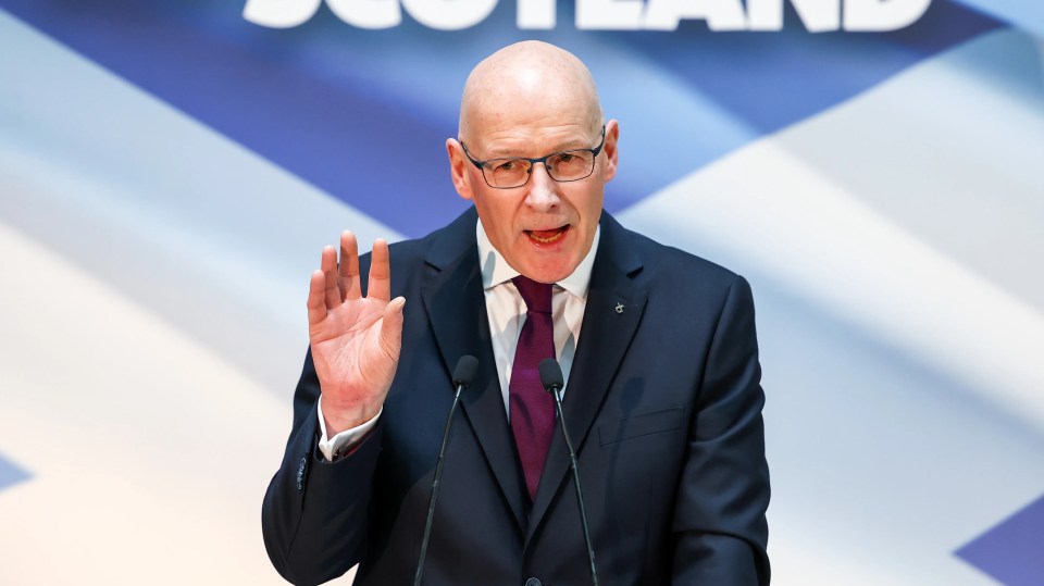 a man in a suit and tie is giving a speech in front of a sign that says scotland