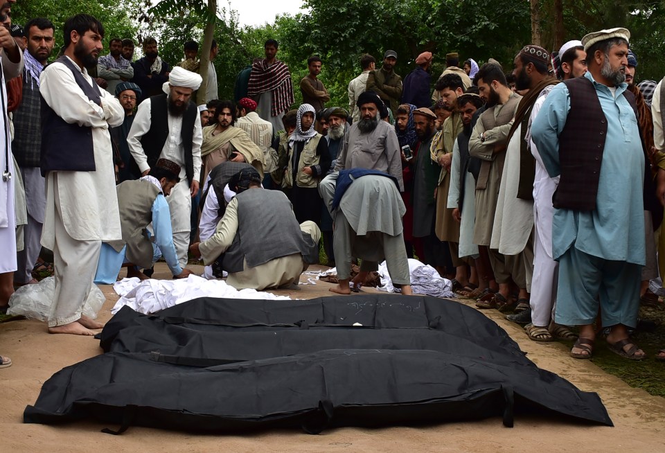 Bodies are placed on the ground and covered in black and white cloth