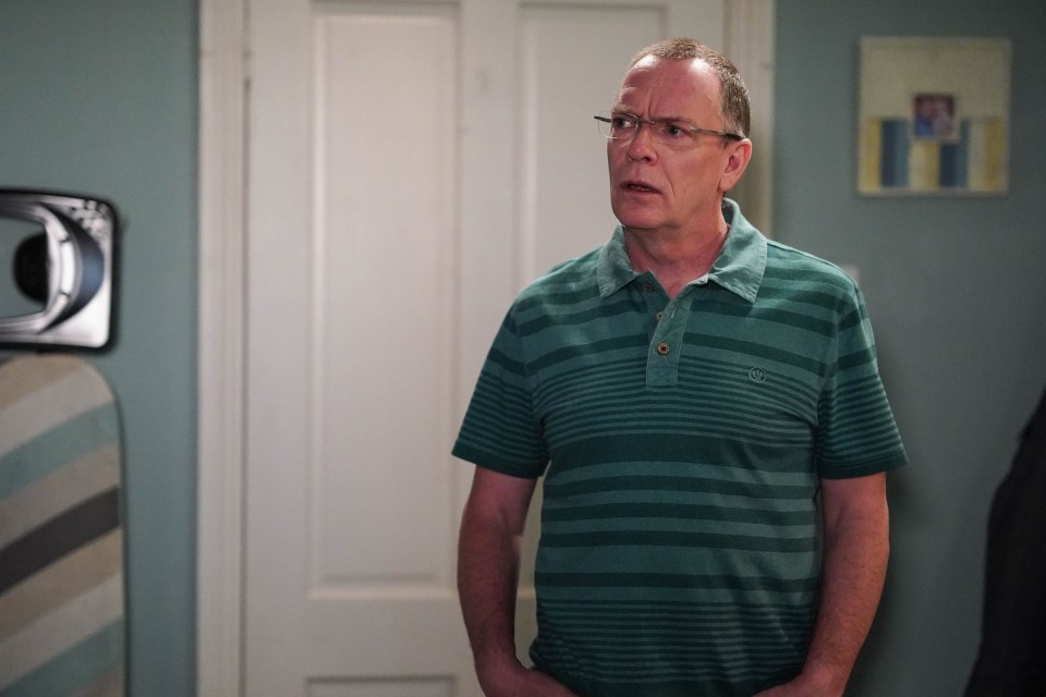 a man wearing glasses and a green striped shirt is standing in front of a door