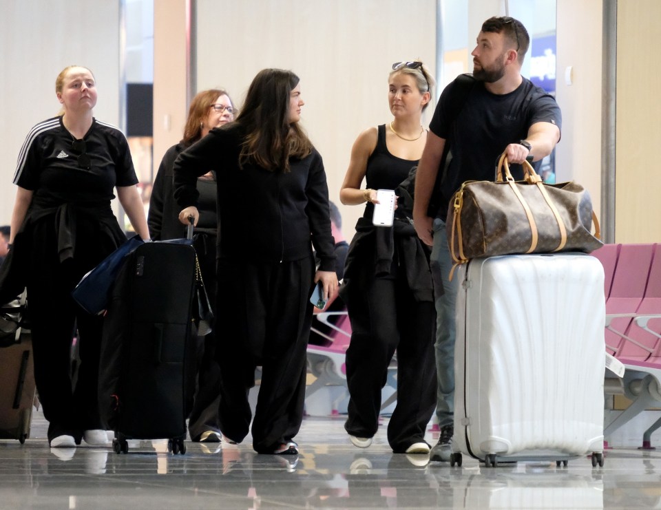 a man carrying a louis vuitton bag walks with a group of people