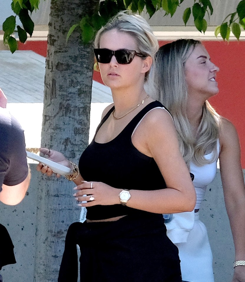 a woman wearing sunglasses and a watch stands next to another woman