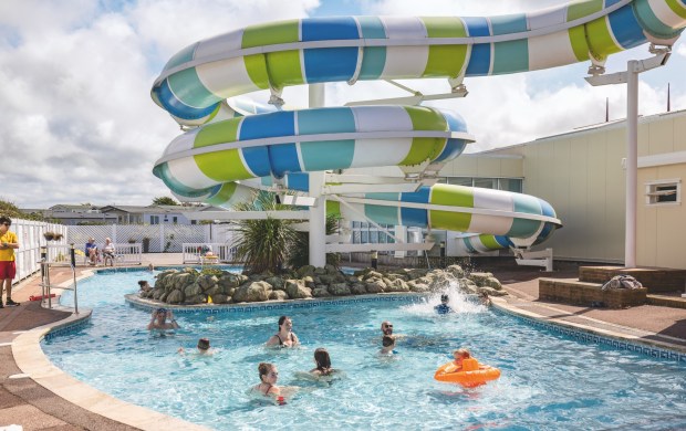 people swimming in a pool with a water slide in the background