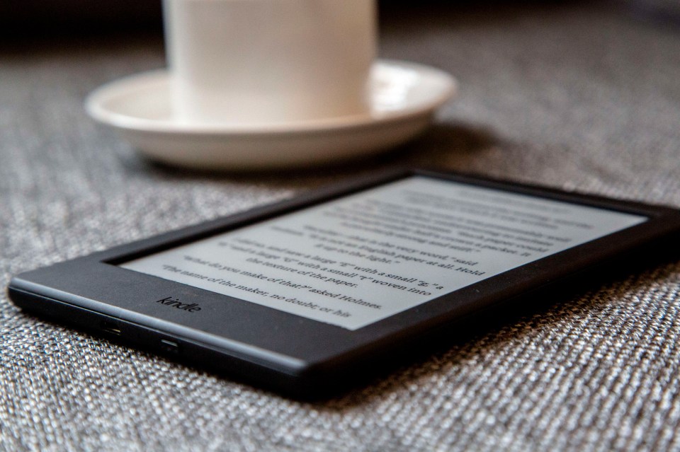 a kindle sits on a couch next to a candle holder