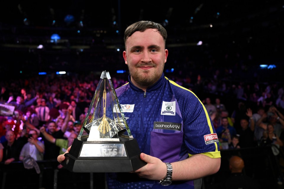 a man holding a trophy that says darts on it