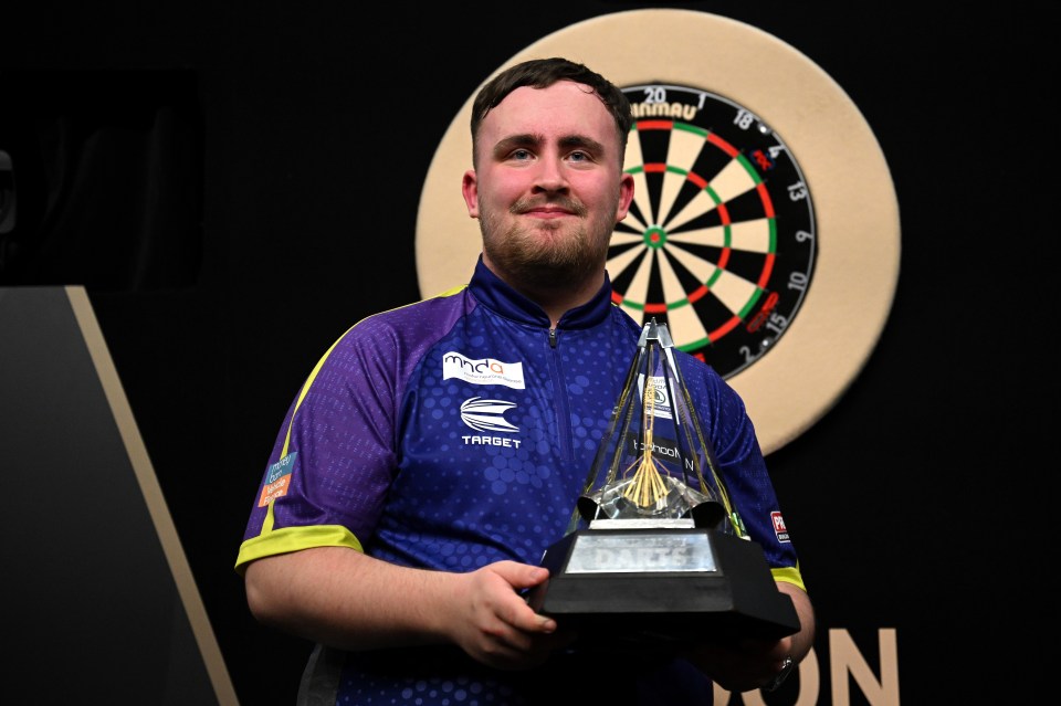 Luke Littler celebrates with the trophy after winning the final match against Luke Humphries at the 2024 BetMGM Premier League Darts Play-Offs at The O2 Arena