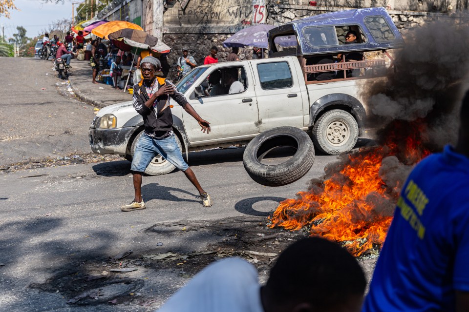 A man sets a tyre on fire during a demonstration following the resignation of Haitian Prime Minister Ariel Henry