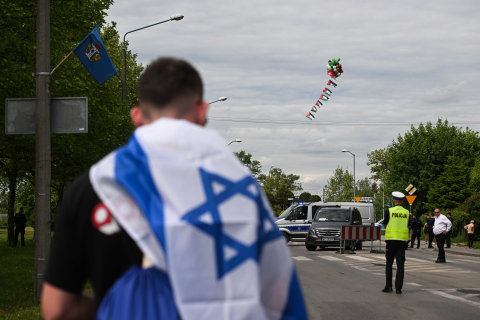 Members of the March of the Living wear Israeli flags as balloons with the Palestinian colours fly in the sky