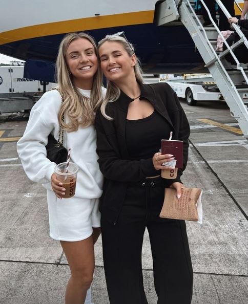 two women are posing for a picture in front of a ryanair plane