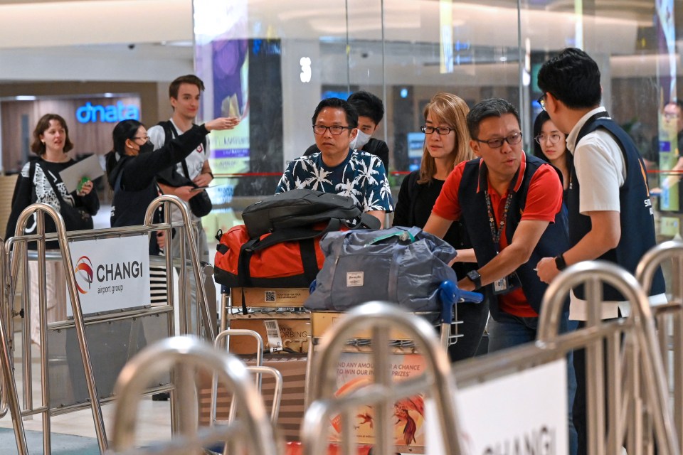 The traumatised flyers, who made an emergency landing in Bangkok, are seen escorted by ground staff upon arrival in Singapore