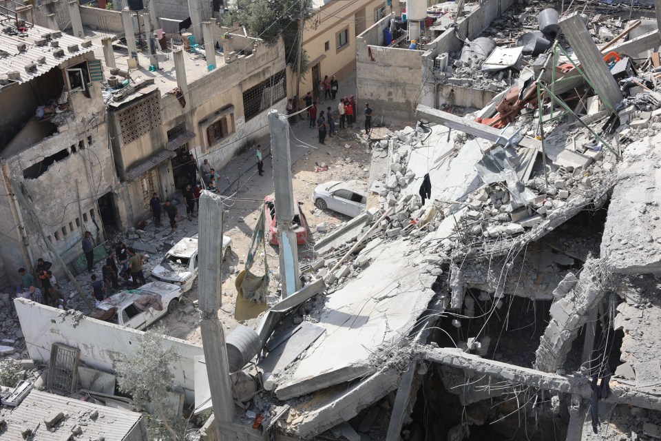 People inspect the damage in the rubble of a building damaged during Israeli strikes