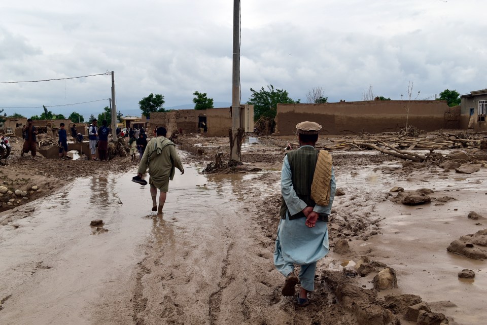 People are seen near their damaged homes after heavy flooding in Baghlan