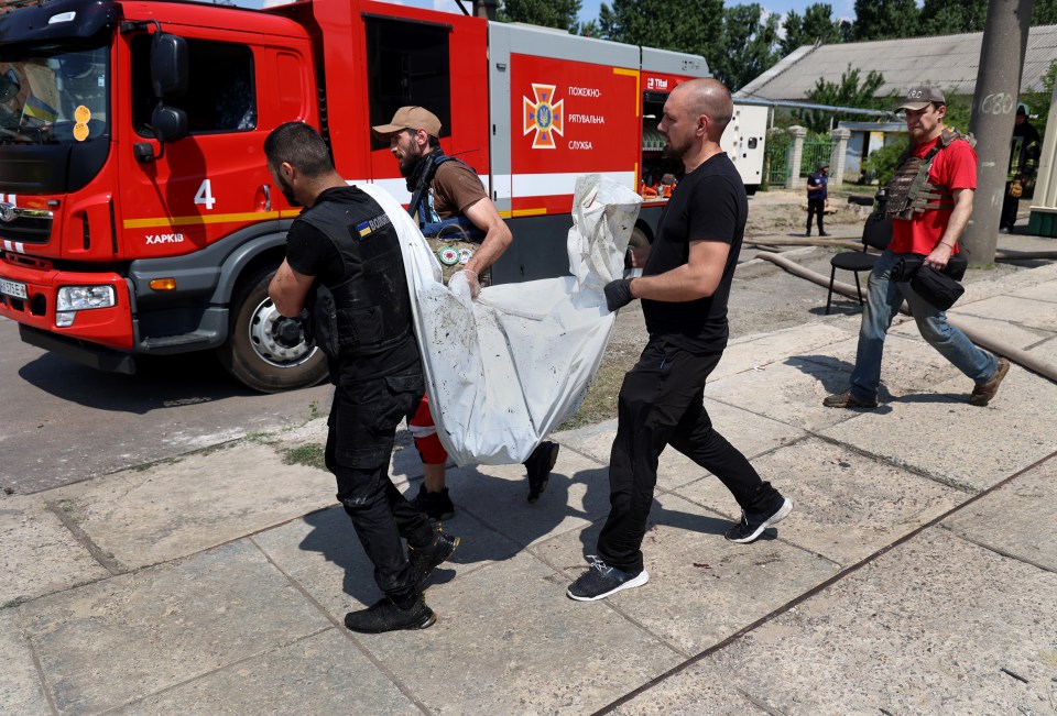 Emergency crews remove a body from the scene wrapped in white plastic