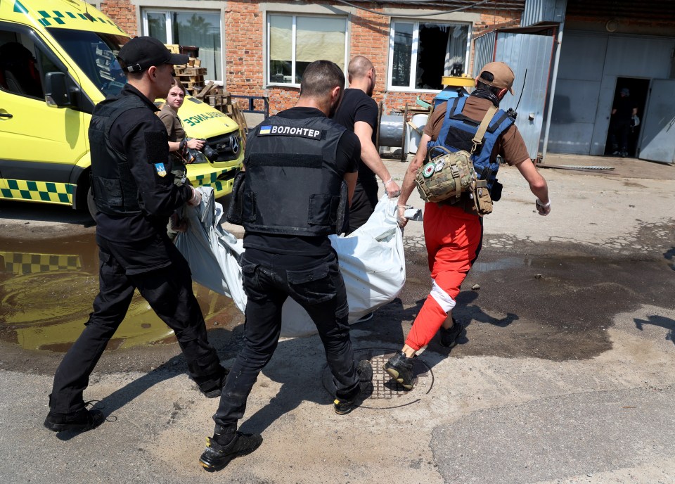 Police and firemen remove dead bodies from the scene