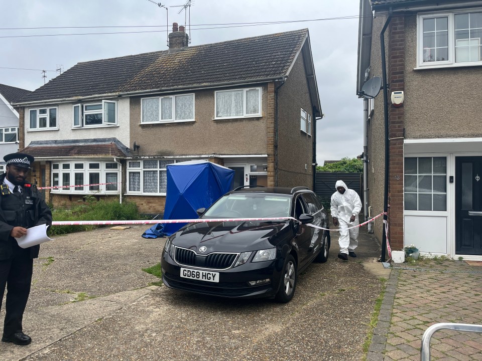 A forensics officer emerges from the house