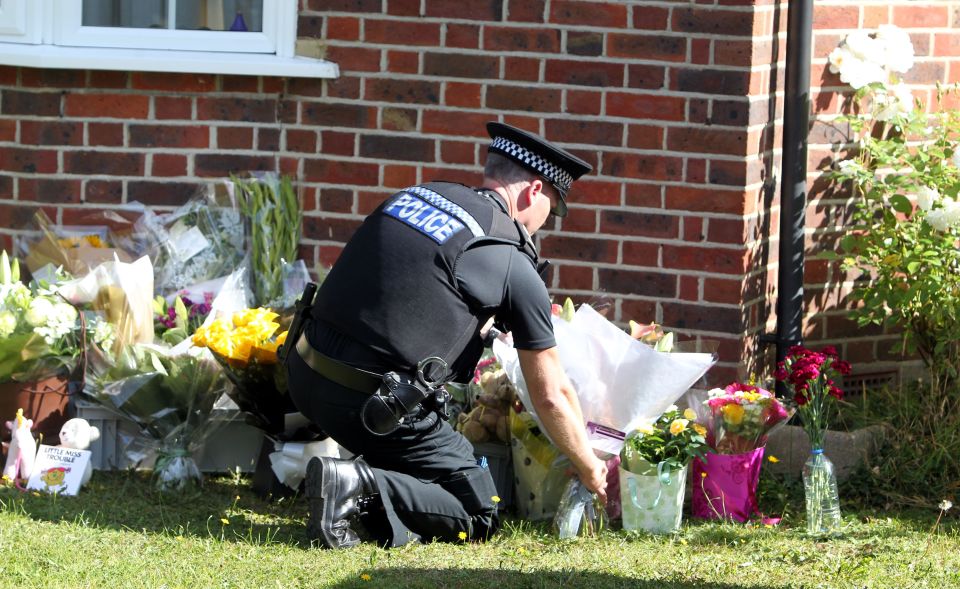 A police officer lays flowers outside the British family's home in Surrey