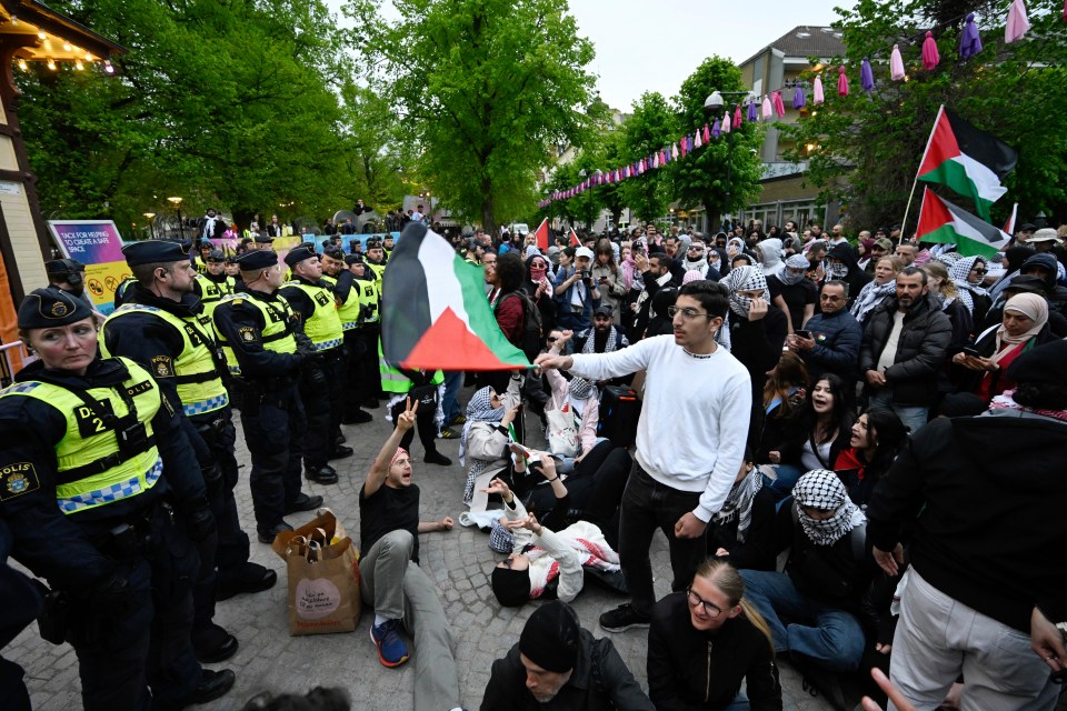 Pro-Palestinian protesters face a wall of police outside Eurovision Village in Malmö