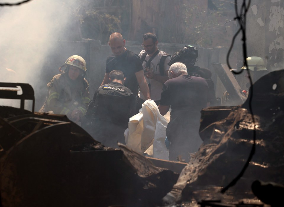 Police and firemen hold a body bag as they prepare to move one of seven killed