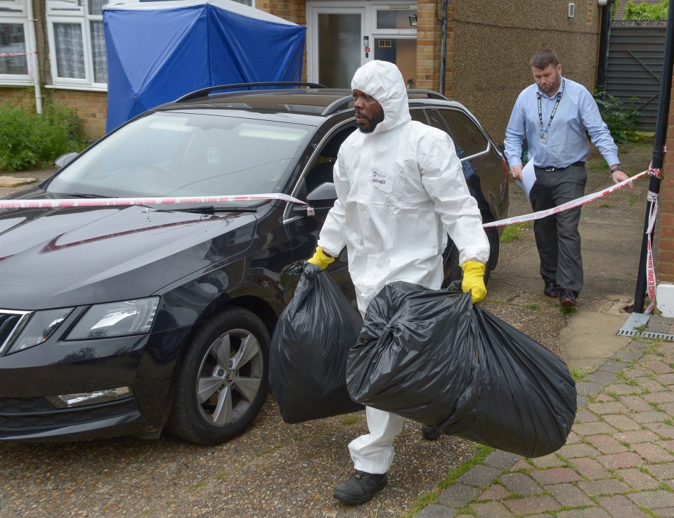 A forensics officer carrying black bin bags at the scene